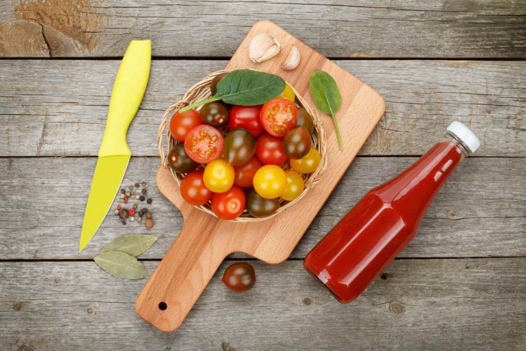 fresh tomatoes and ketchup bottle on a wooden background
